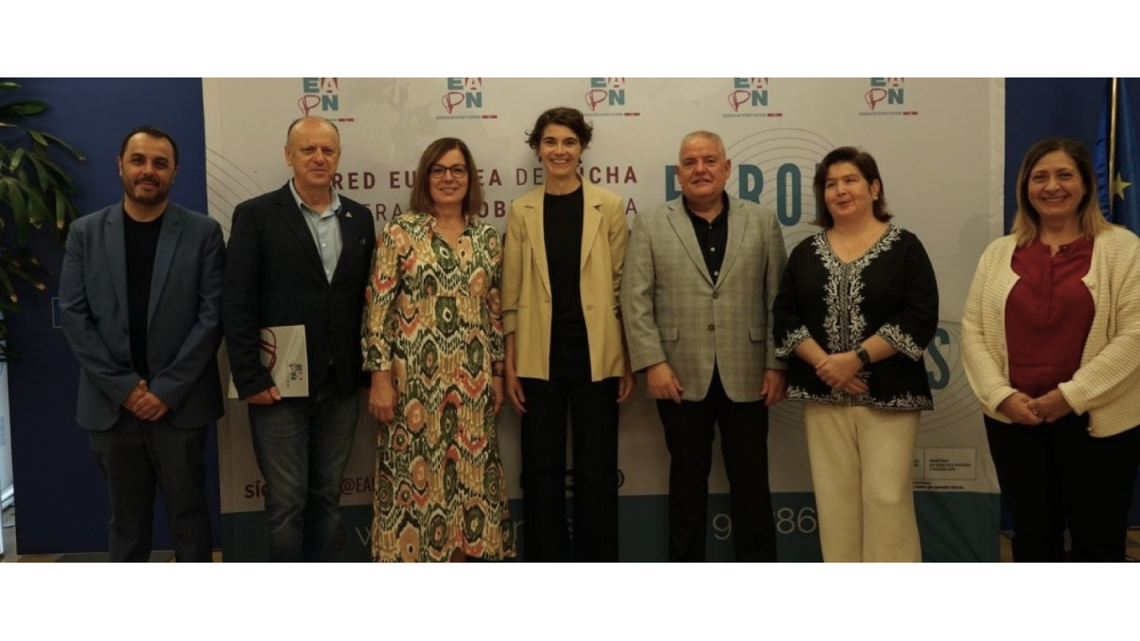 Un grupo de 7 personas posan de pie delante de un photocall