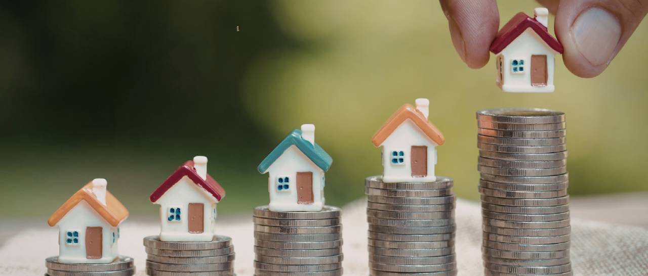 Ilustración de unas torres de monedas con casitas encima