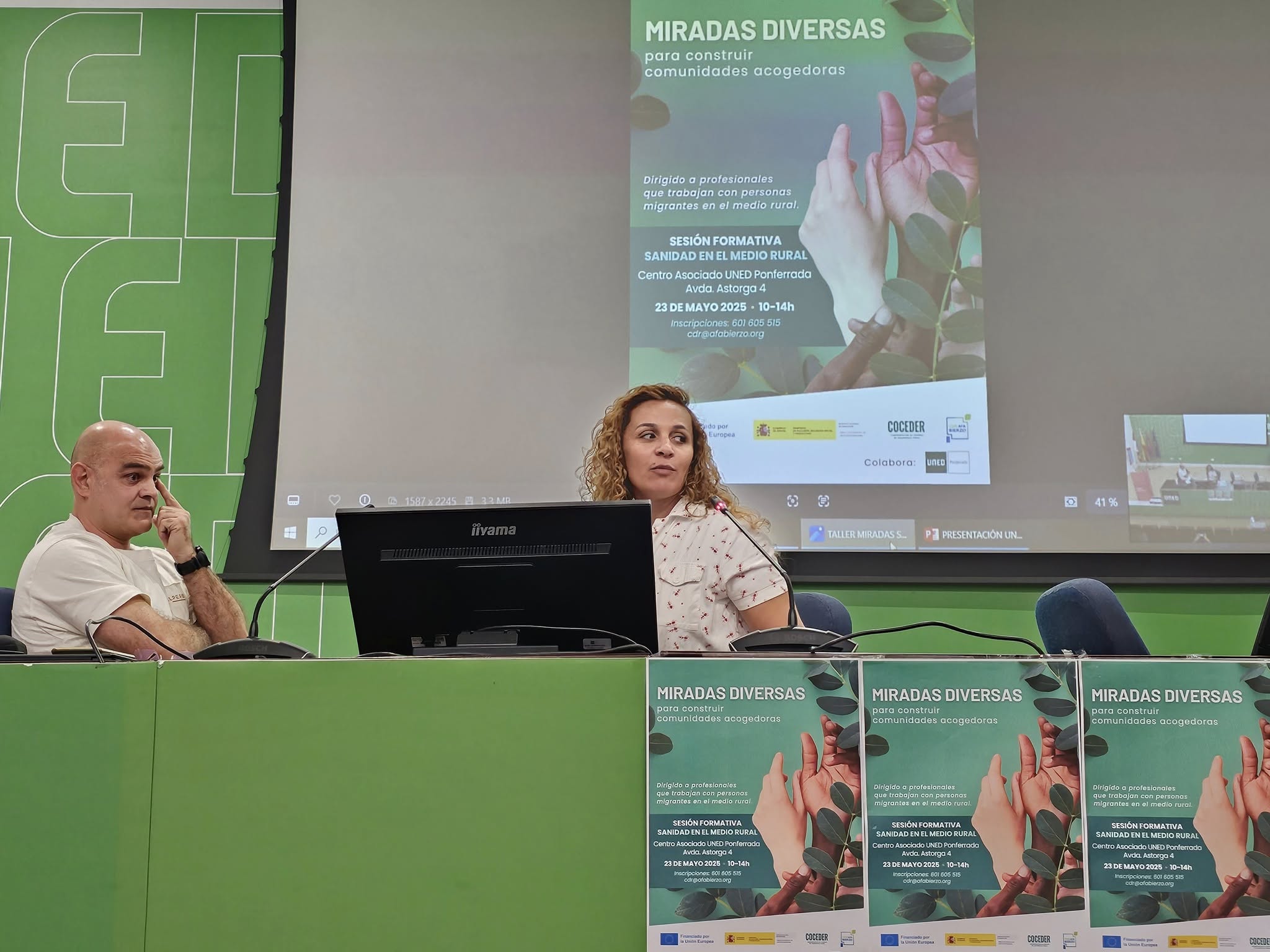 una mujer habla sentada junto a un hombre y con un cartel "Miradas diversas para construir comunidades acogedoras"