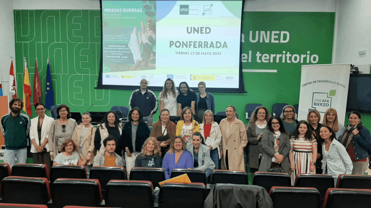 un grupo de personas de pie posa delante de un cartel "Miradas diversas" en el salón de actos de la UNED Ponferrada