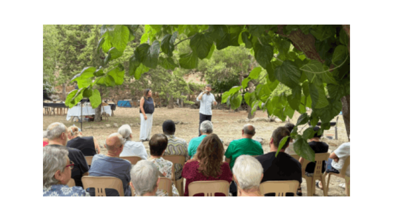 Un grupo de personas de espaldas escucha a un hombre y una mujer hablando