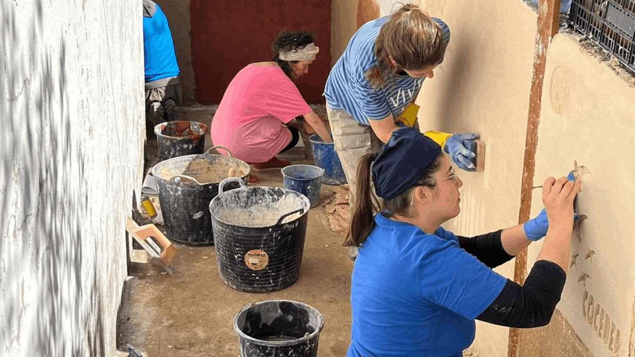 Unas mujeres trabajan alisando una pared 