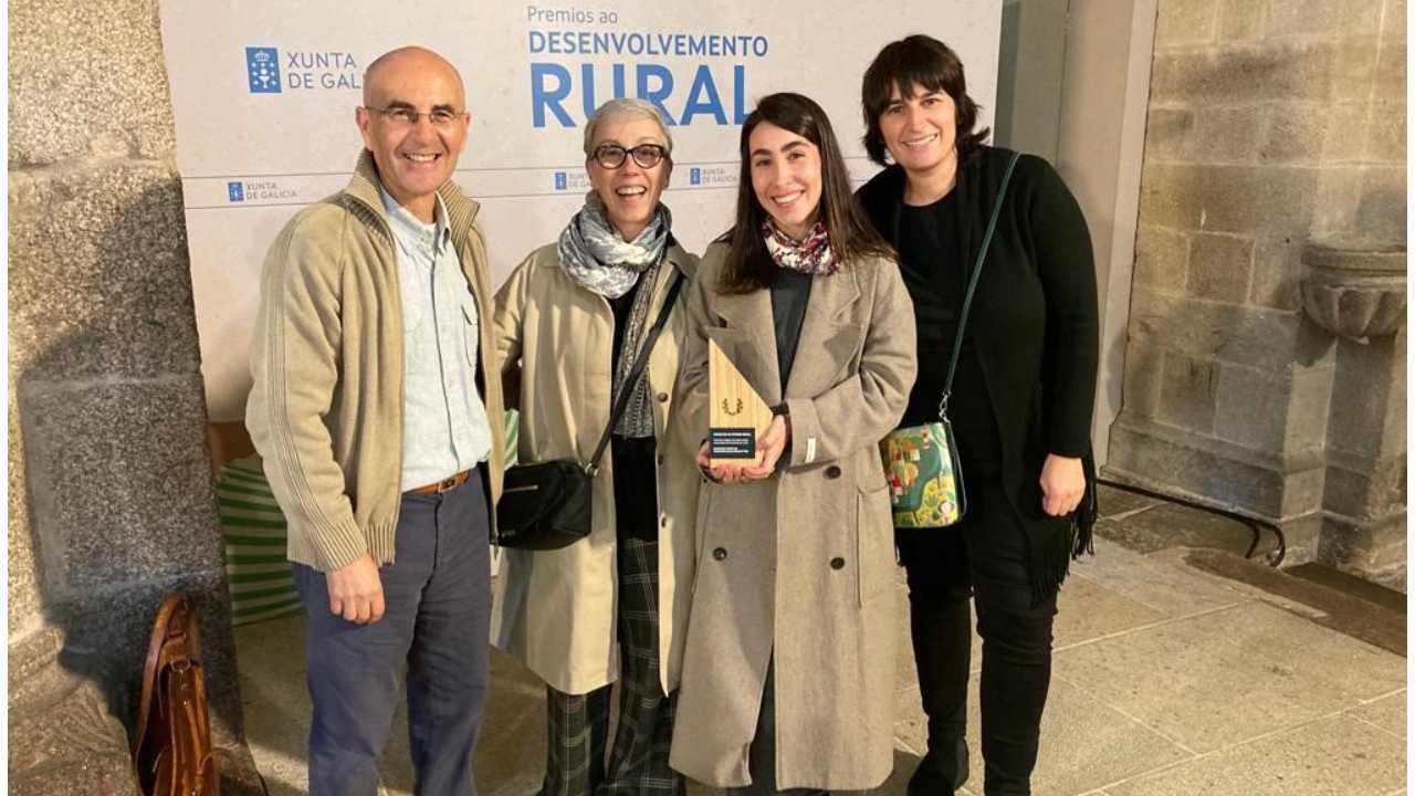 Cuatro personas posan con un premio detrás de un cartel de la Xunta de Galicia