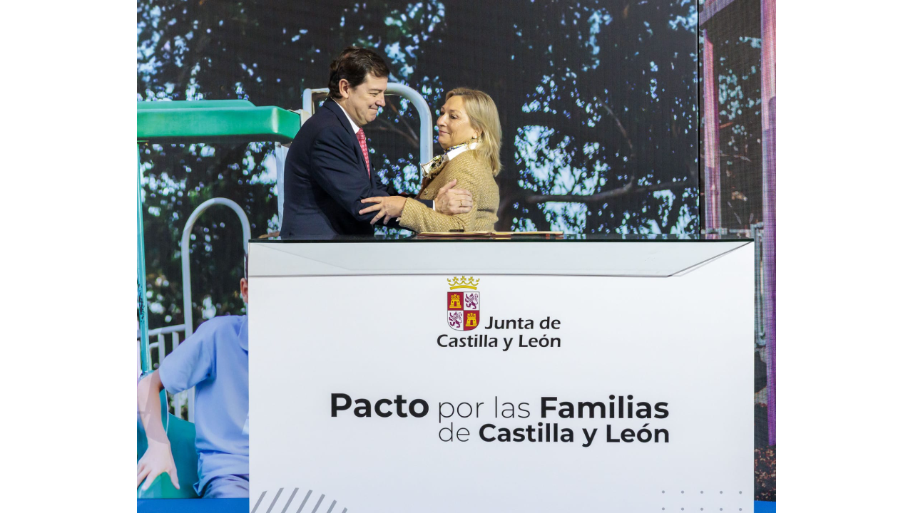 Un hombre y una mujer se saluda delante de un atril del Paco por las Familias de Castilla y León