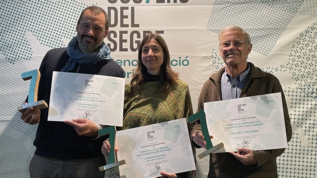 Dos hombres y una mujer sostienen unos premios en la mano y un certificado