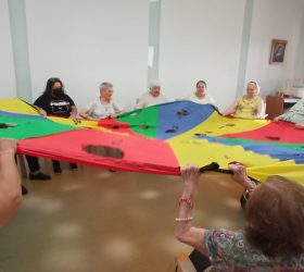 Grupo de personas en circulo sujetando una tela con triángulos de colores